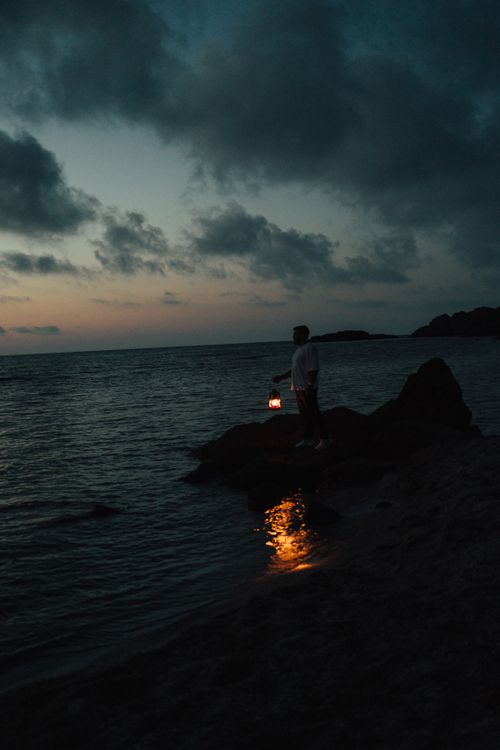 Free Mystical seashore silhouette holding a lantern at dusk in Türkiye. Stock Photo