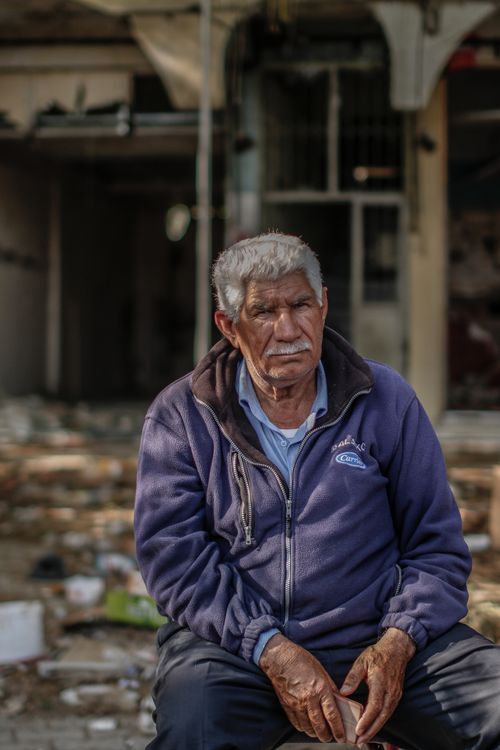 Free Elderly man in a blue jacket sitting outdoors in an urban environment. Stock Photo