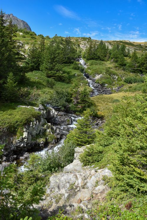 Free Beautiful mountain landscape with a cascading river surrounded by lush greenery. Stock Photo
