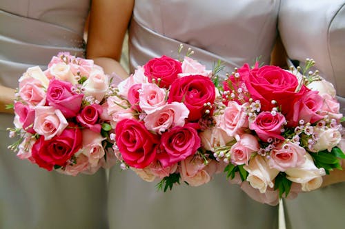ピンクと赤のハイブリッドティーローズの花束を保持している3人の女性