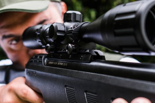 Shooter aiming a scoped rifle