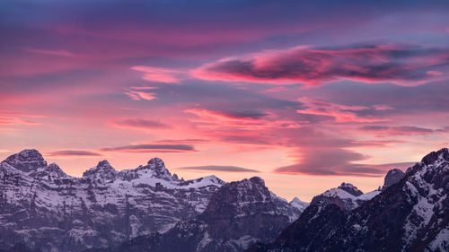Free Breathtaking view of snowy mountain peaks under a vibrant sunset sky. Stock Photo