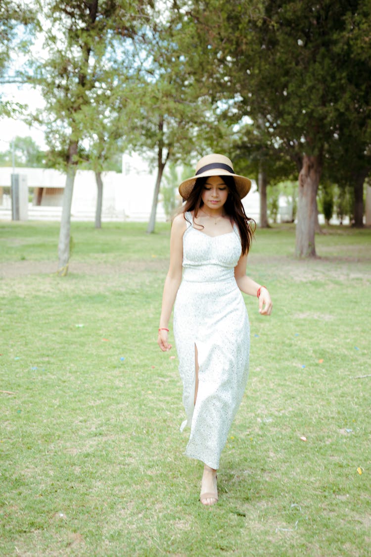 Young Woman In A Dress And Hat Walking In The Park