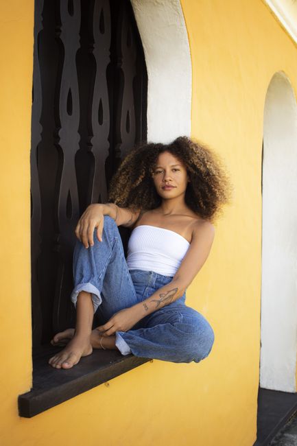 Portrait of a young woman sitting casually on a windowsill in Porto Seguro, Brazil.