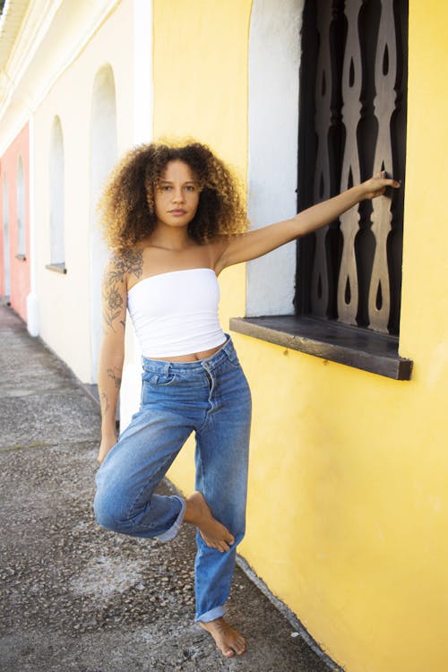 Young Woman in a White Top and Jeans Standing Barefoot on the Pavement