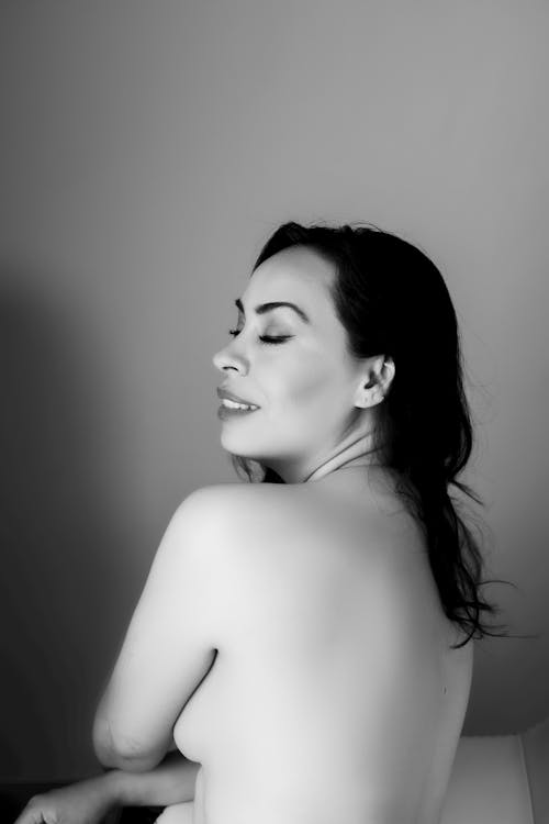 Black and White Picture of a Topless Woman Standing with Eyes Closed 