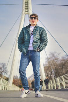 在现代城市桥梁上，时尚的年轻人穿着绿色夹克和牛仔裤，展示冬季时尚