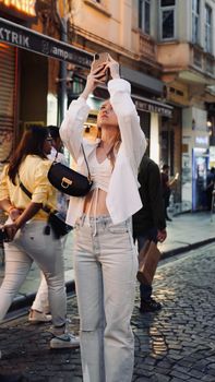 A young woman captures city vibes with her phone in an urban environment.