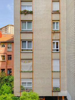 Close-up view of an apartment building facade in Bilbao with lush greenery below.