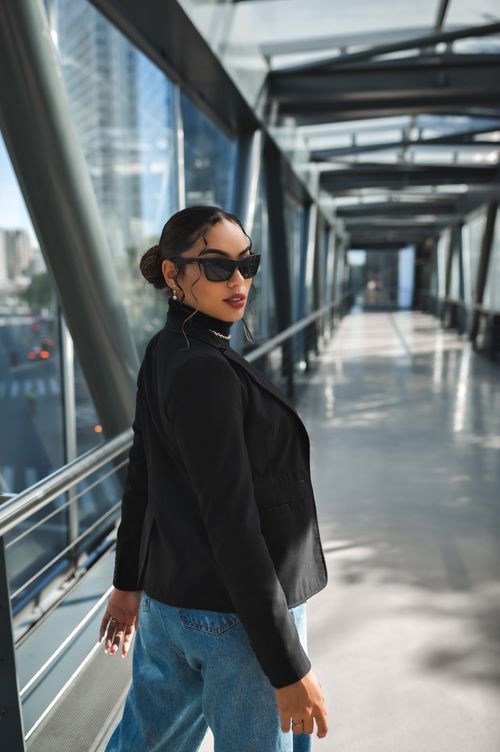 Free Fashionable woman in sunglasses stands on a modern urban footbridge, showcasing sleek style. Stock Photo