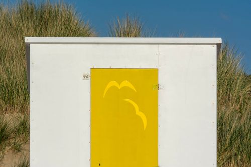 Free Bright beach hut with a yellow door featuring a seagull design on the coast of Cadzand, Netherlands. Stock Photo
