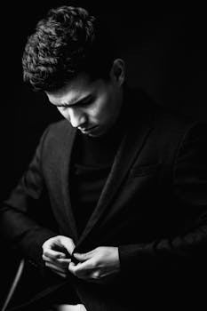 Stylish black and white portrait of a man adjusting his suit with a focused expression.