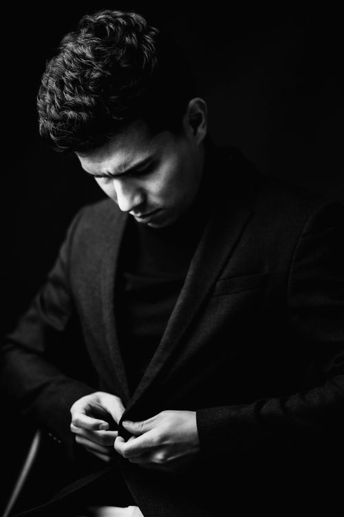 Free Stylish black and white portrait of a man adjusting his suit with a focused expression. Stock Photo