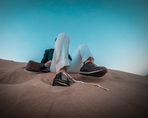 Person Sitting on Brown Sand