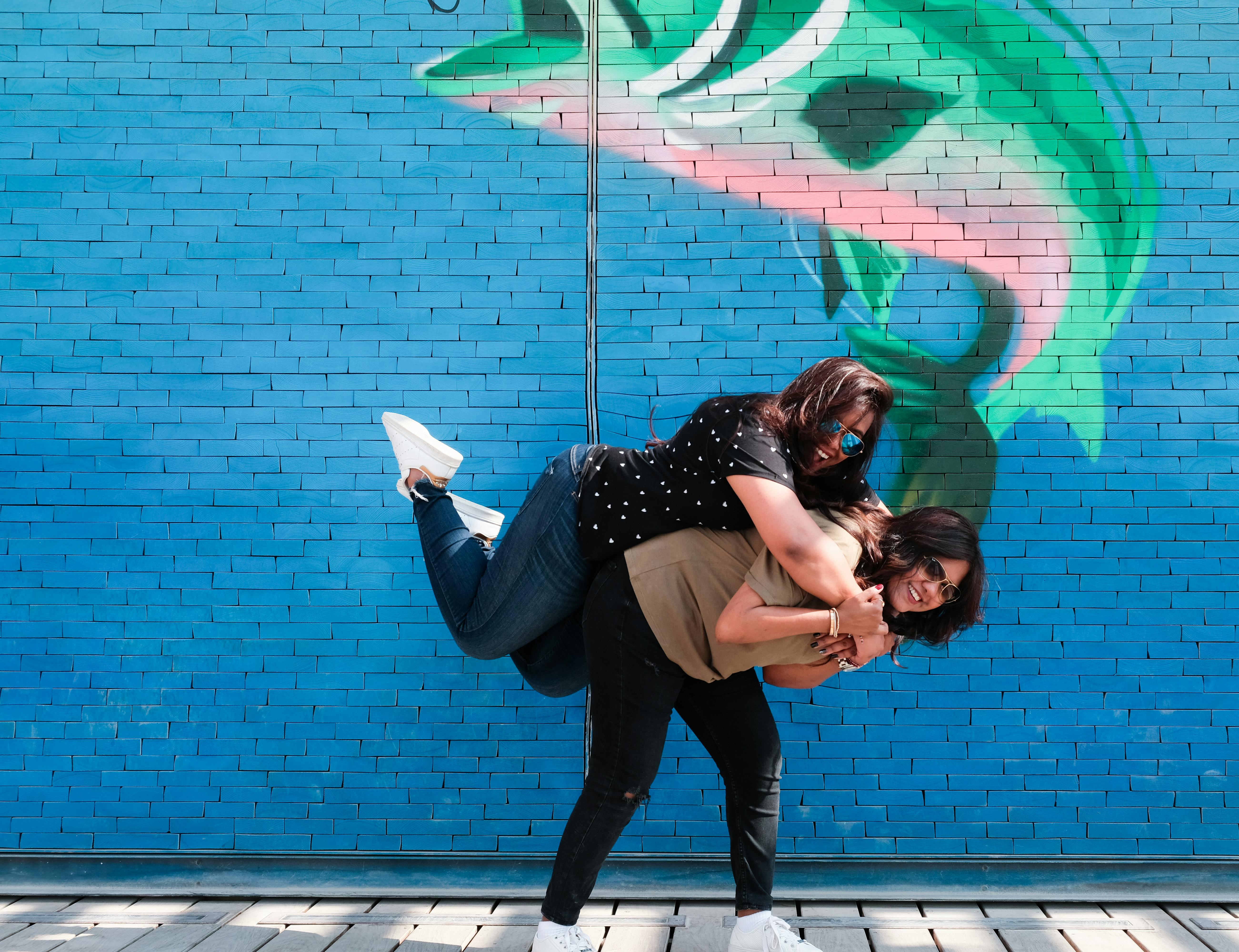 两个女人在五颜六色的涂鸦墙前开心玩耍，捕捉到了欢乐和友谊的时刻