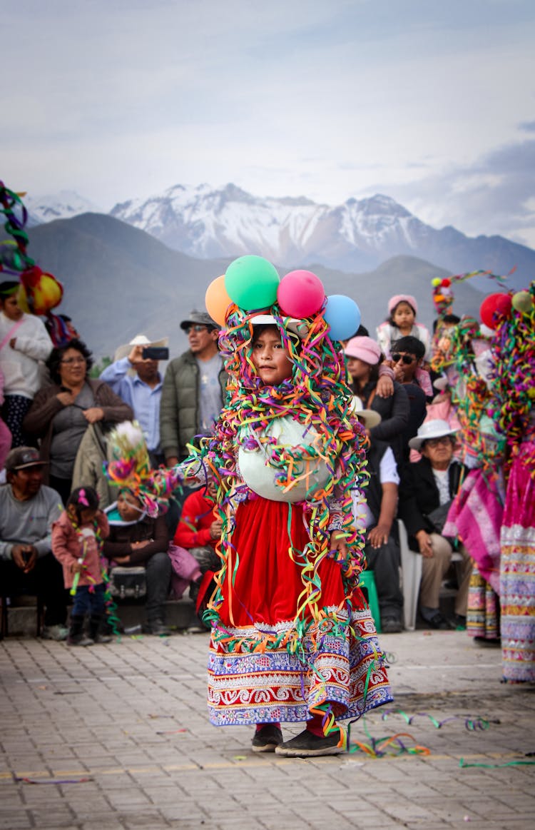 People Watching Child In Traditional Clothing