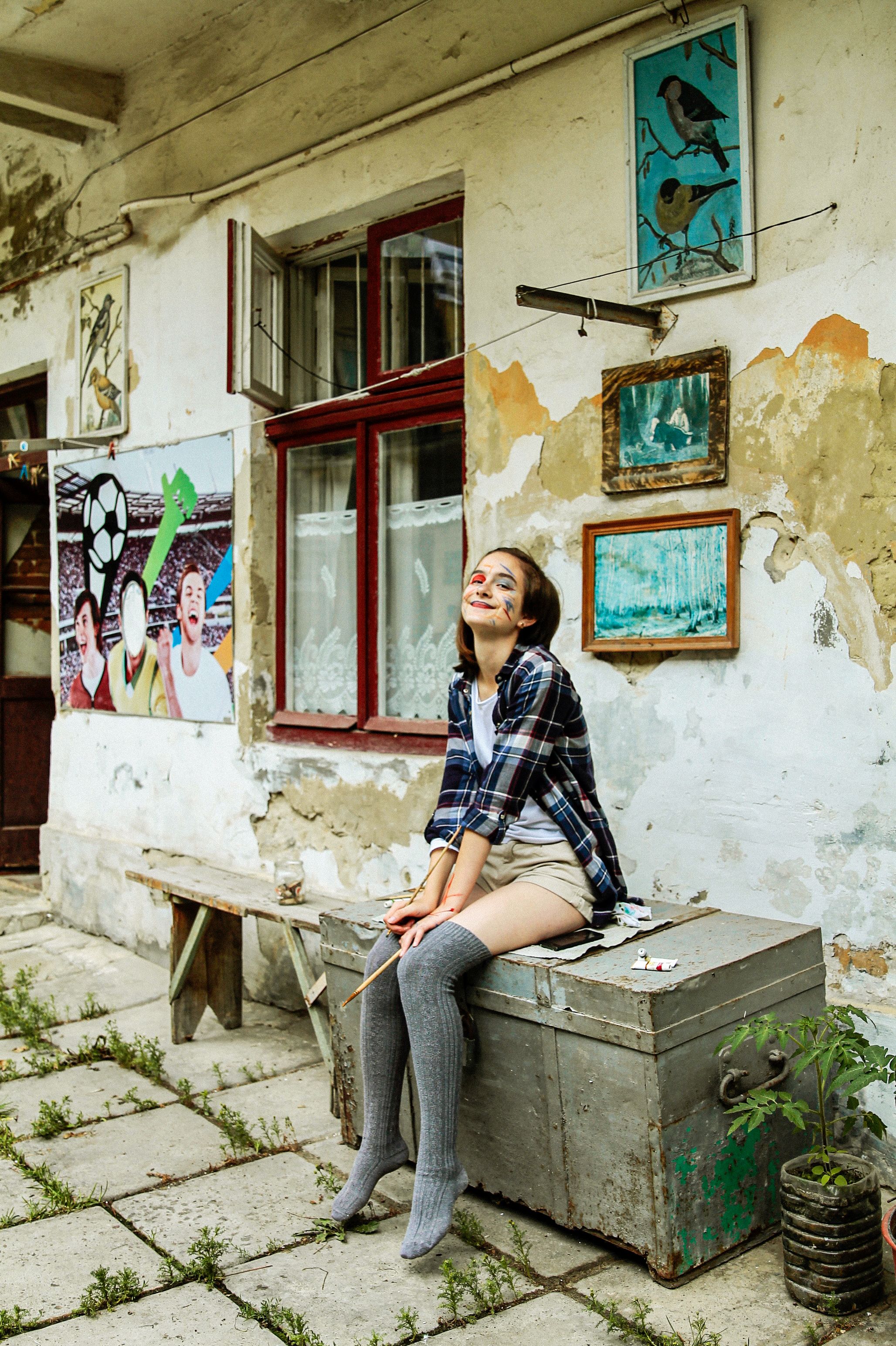 Smiling woman seated in a creative urban environment with art-filled walls.