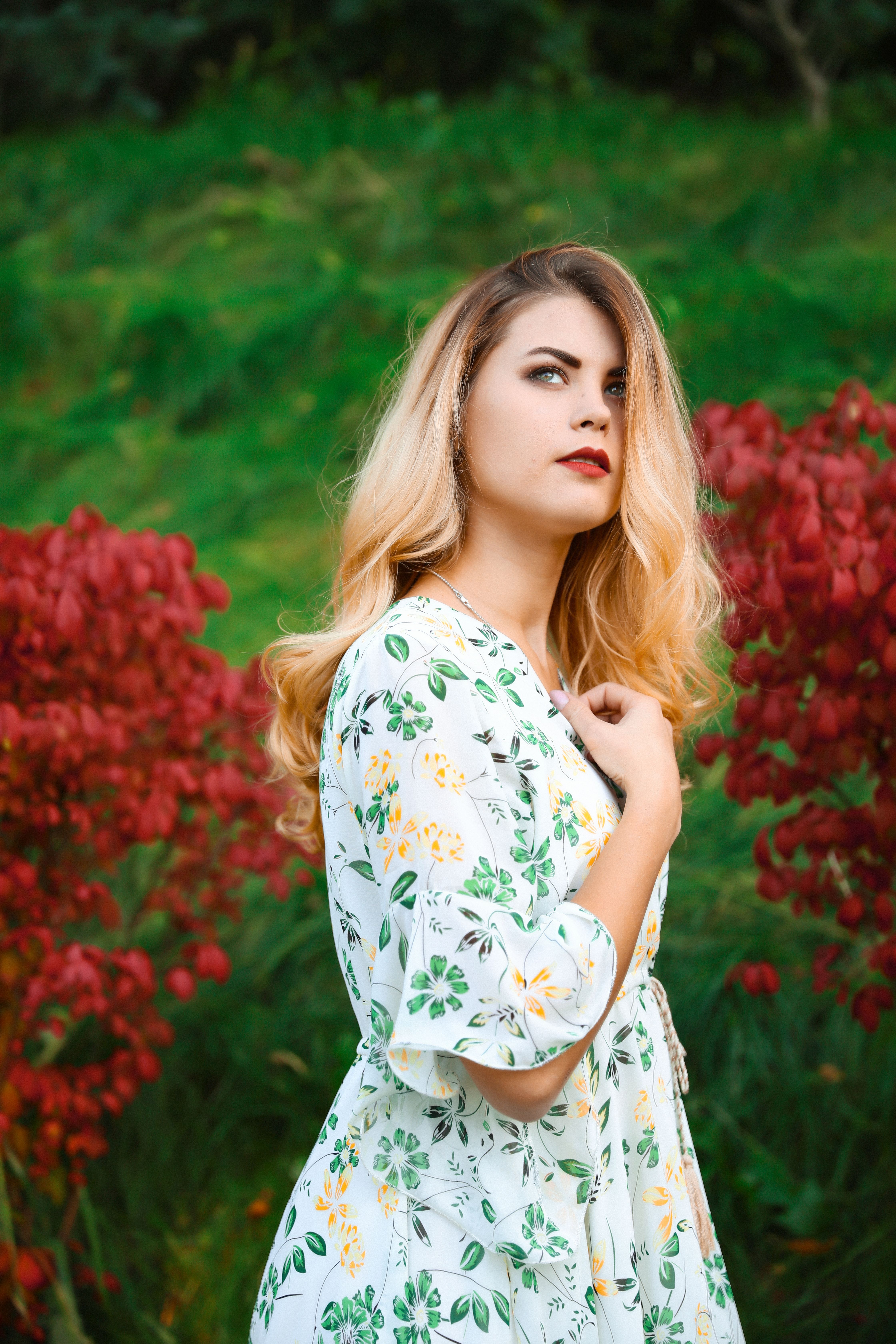 Young Woman in a Floral Dress Standing in a Garden · Free Stock Photo