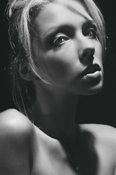 Dramatic black and white portrait of a woman with striking light and shadows, creating a timeless feel.