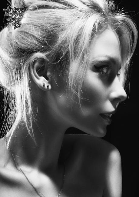Artistic black and white portrait of a blonde woman with elegant makeup in profile view.