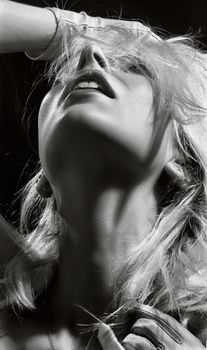 Dramatic black and white portrait of a young woman posing with hair cover.