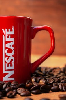 Red mug surrounded by coffee beans creates a cozy and inviting atmosphere.