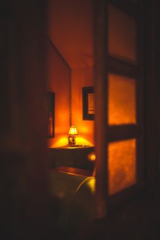 Cozy room with a warm lamp light seen through an open door, creating a welcoming ambiance.