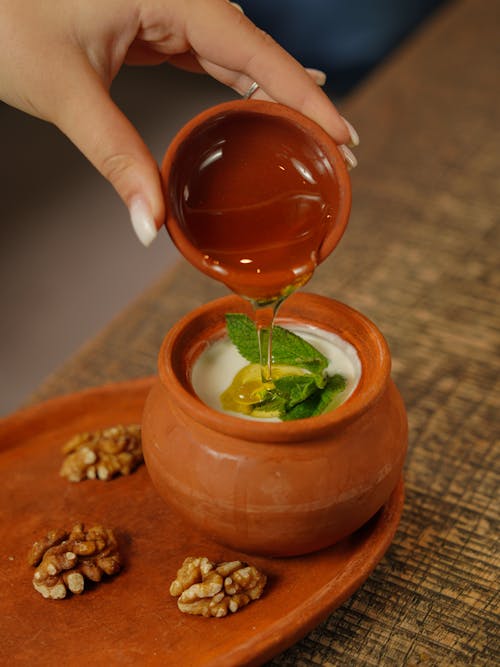 Close-up of Woman Pouring Honey into a Dessert 