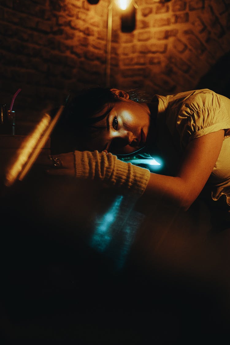 Young Woman Putting Her Head On The Counter In A Dark Interior 