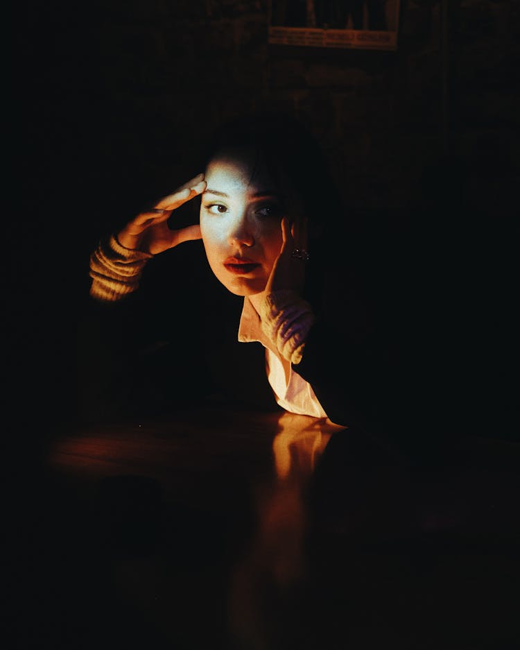 Illuminated Face Of A Woman In A Dark Room 