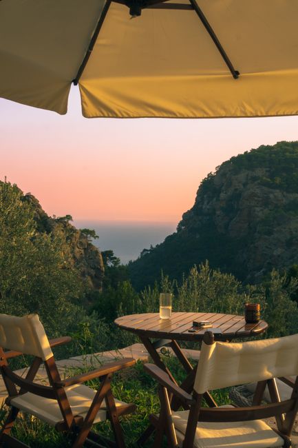 Charming outdoor seating in Arıklı, Türkiye with mountain and sea view during sunset.