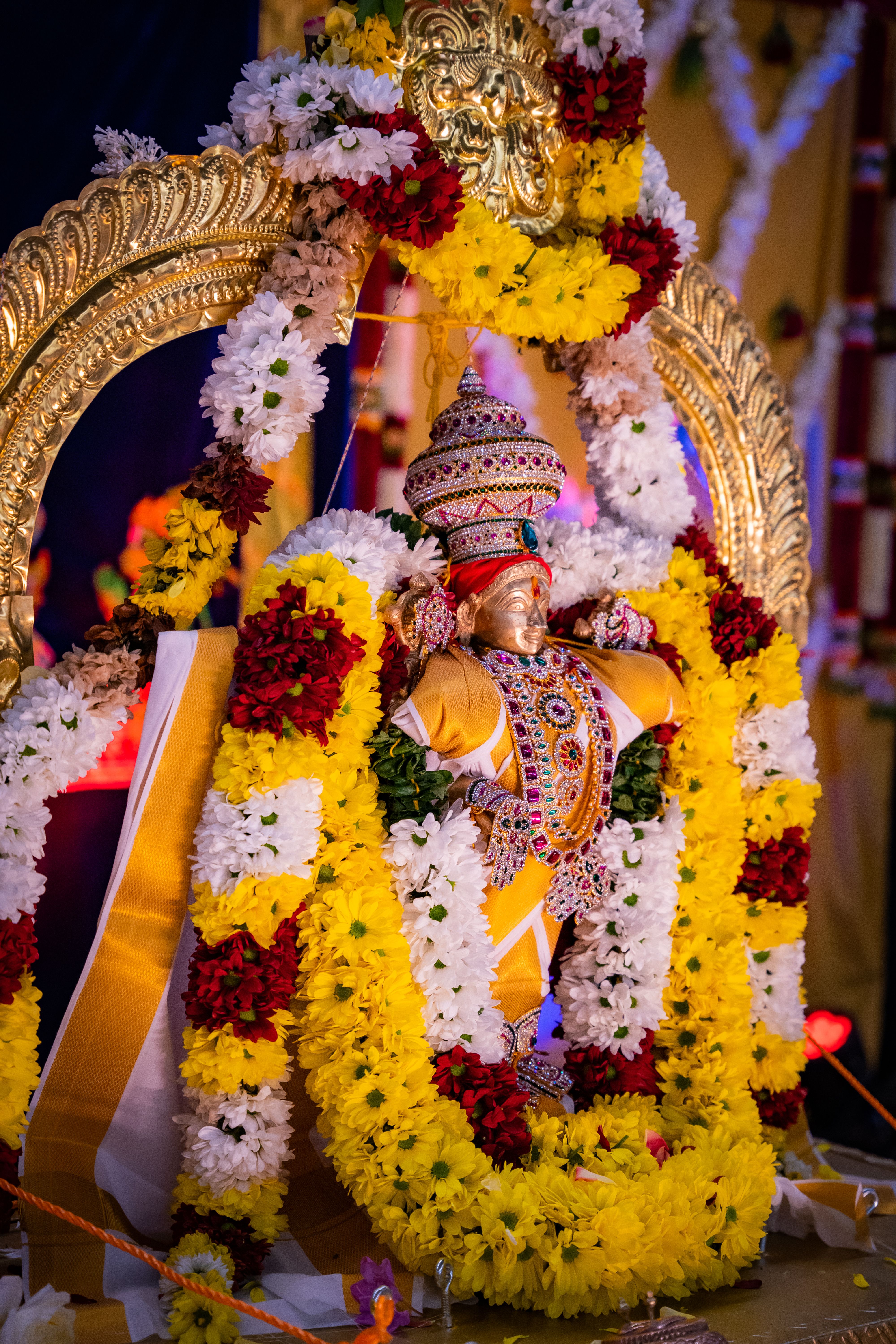 A beautifully adorned Hindu deity statue wrapped in a vibrant garland during a festive celebration.