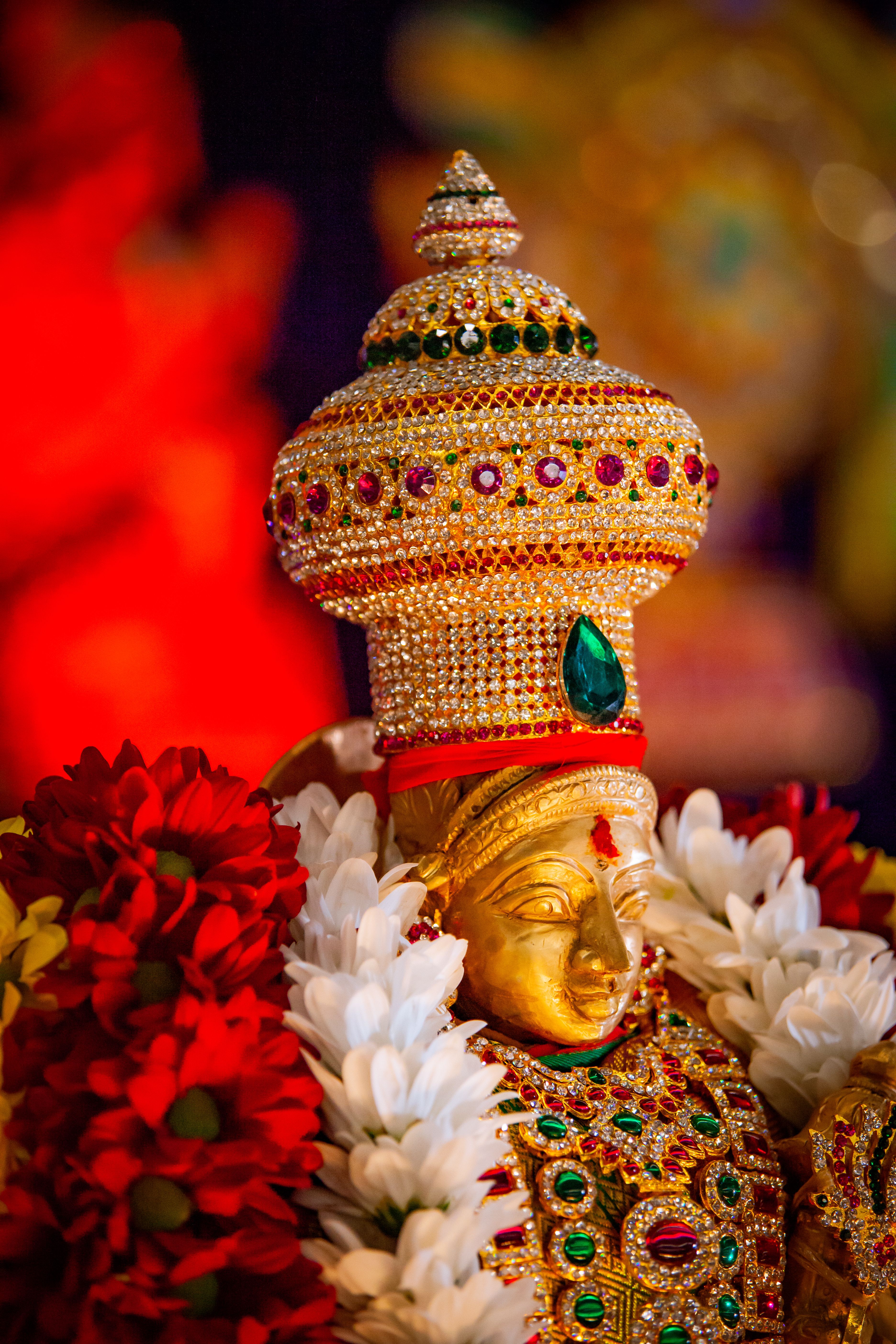 Close-up of a Hindu deity statue adorned with colorful jewelry and flowers, perfect for religious and cultural themes.
