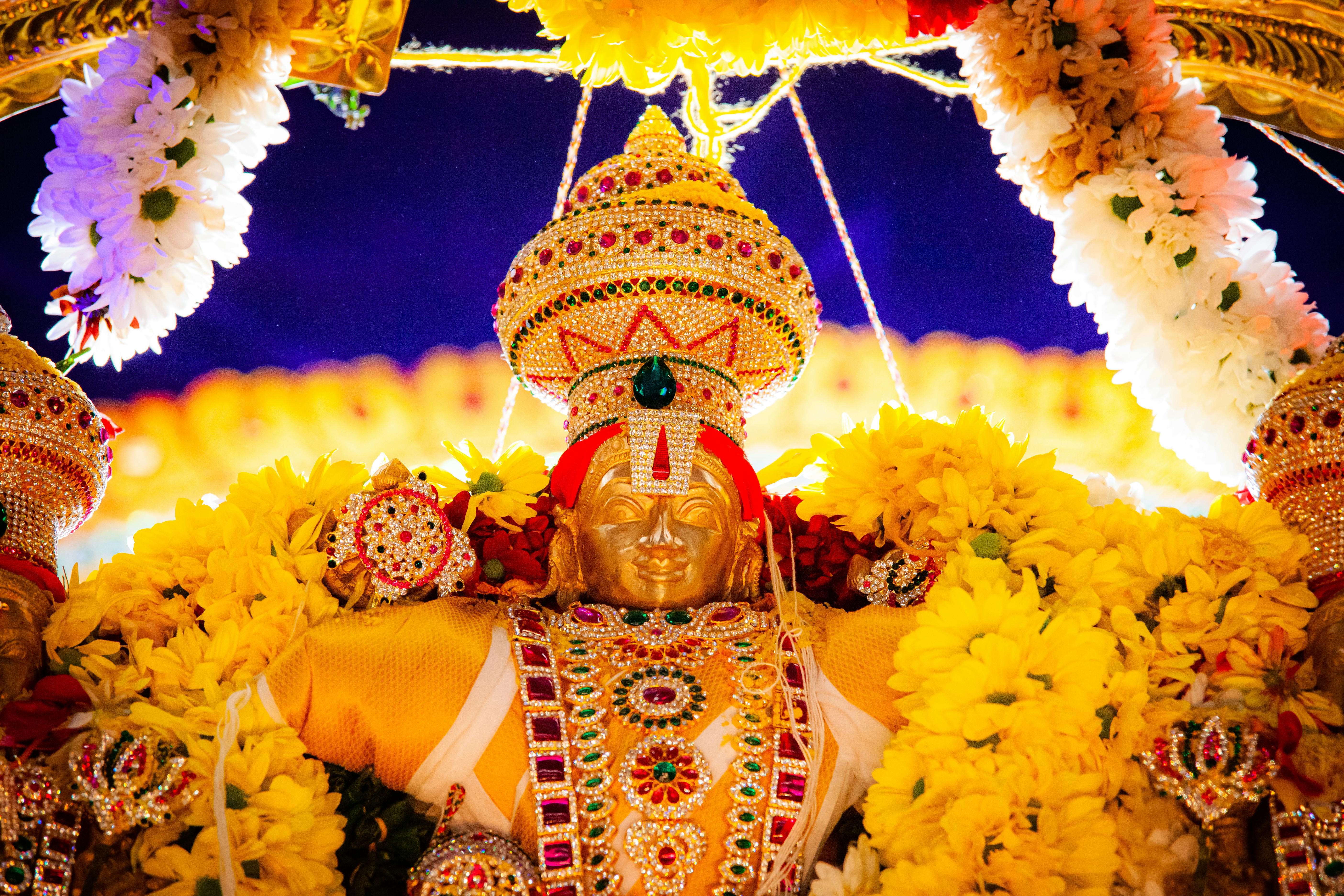 A richly adorned Hindu deity statue surrounded by vivid flowers, showcasing traditional craftsmanship.