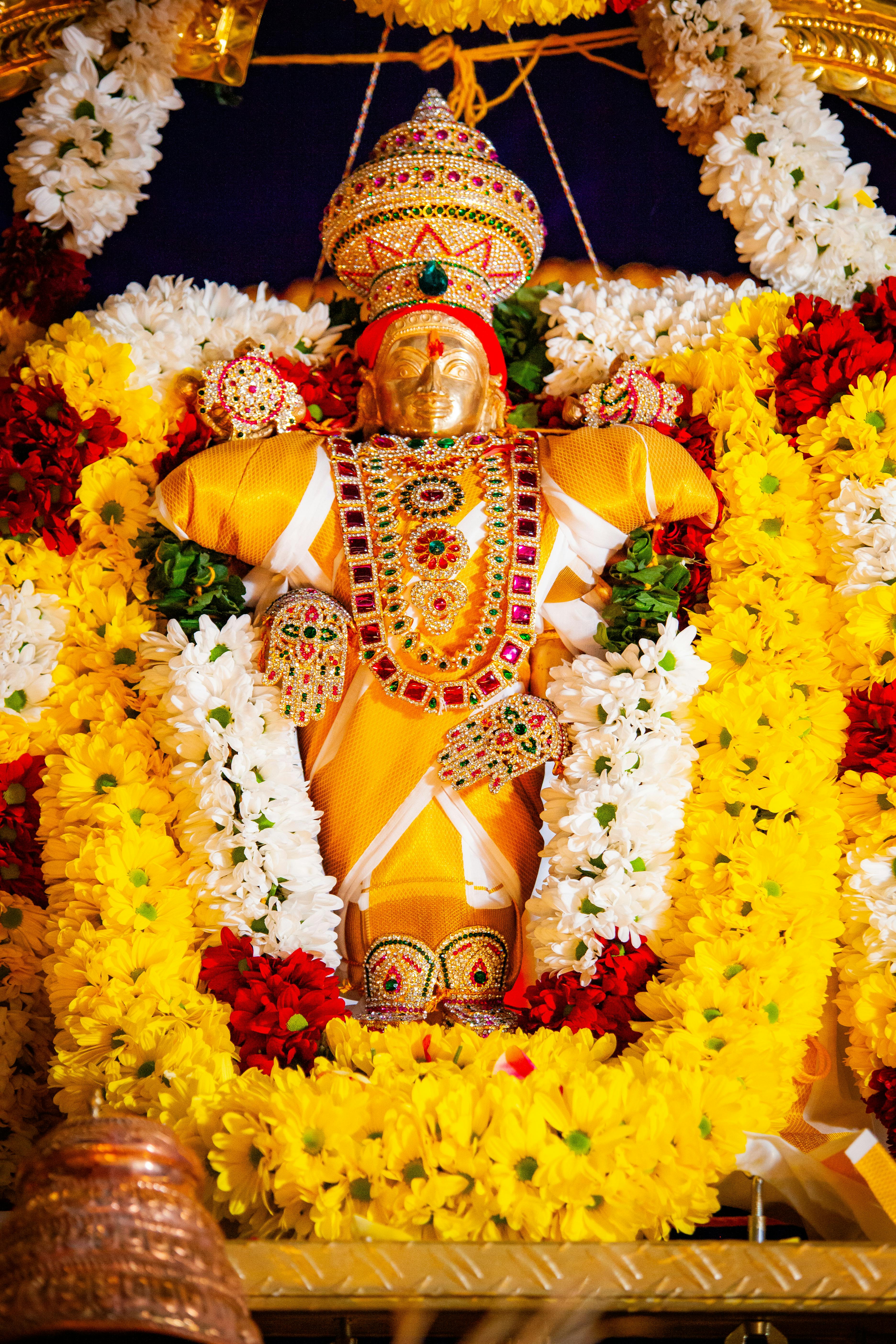 Vibrant deity figure adorned with colorful flowers and ornaments, representing Hindu festival decoration.