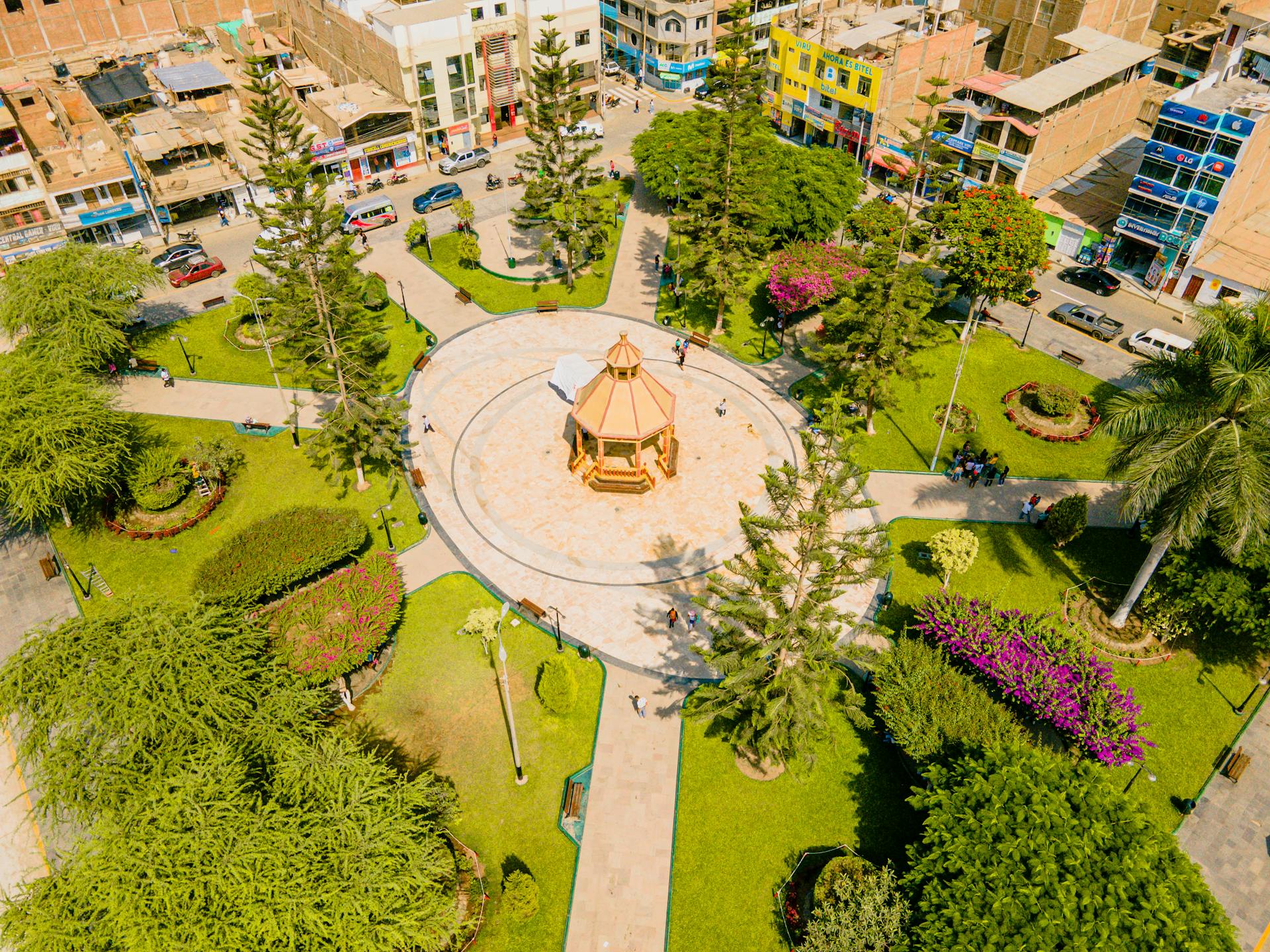 A vibrant aerial shot of a city park with pathways and a central gazebo surrounded by lush greenery.