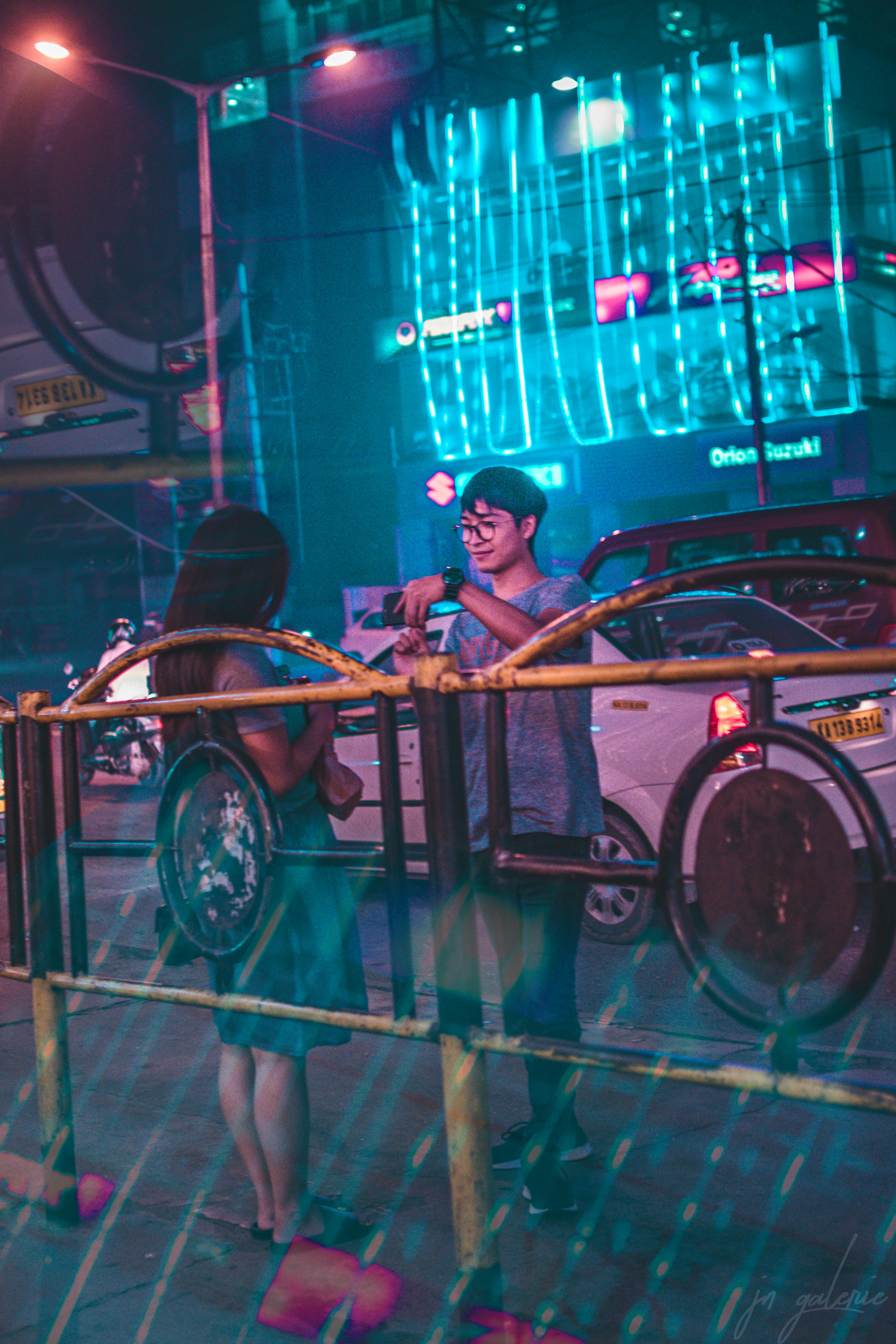 霓虹灯照亮的街道上，一对夫妇正在互动，捕捉着充满活力的城市夜生活