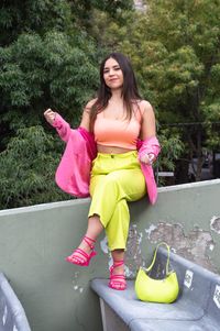 Woman in neon green trousers on a rooftop ledge — photo by Roman Israel Terron Flores on Pexels