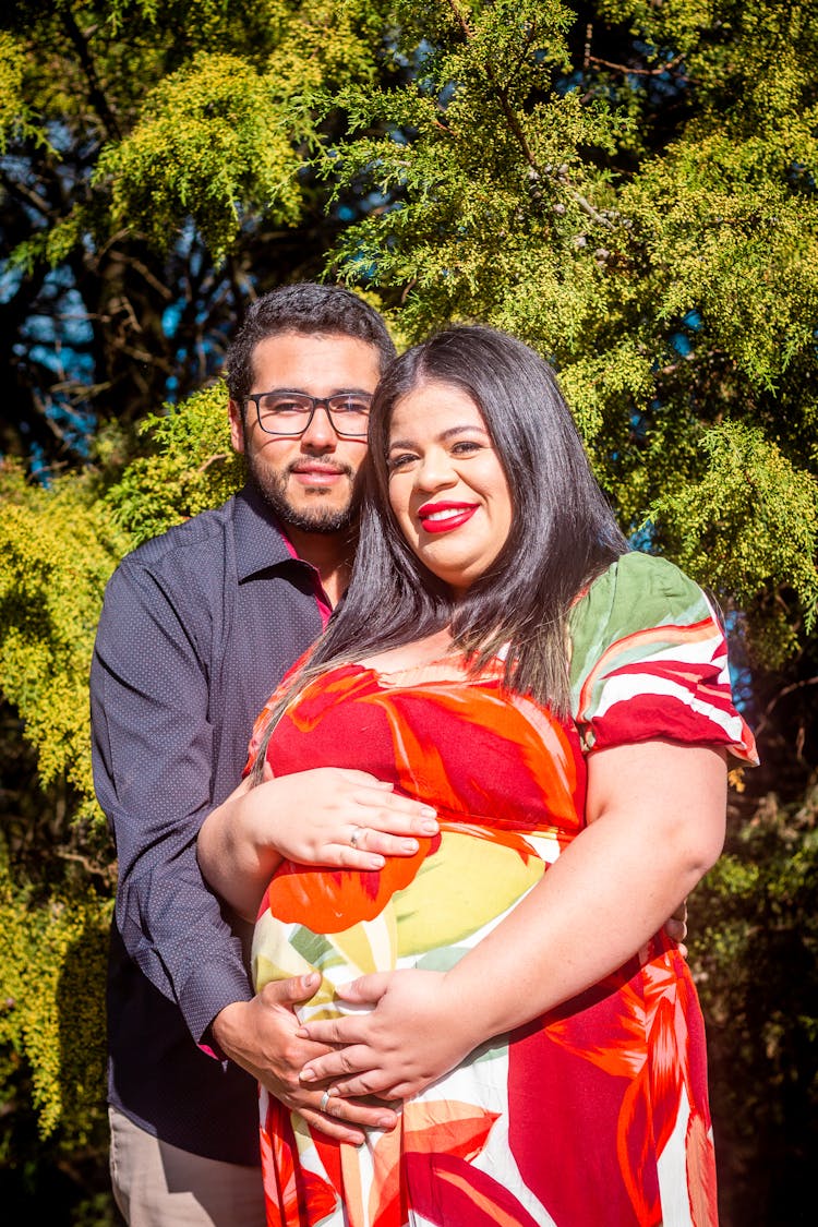 Man Embracing His Pregnant Wife In A Park