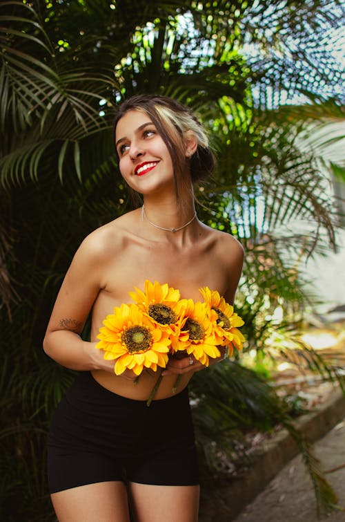 Portrait of a Shirtless Girl Covering her Chest with Blooming Flowers