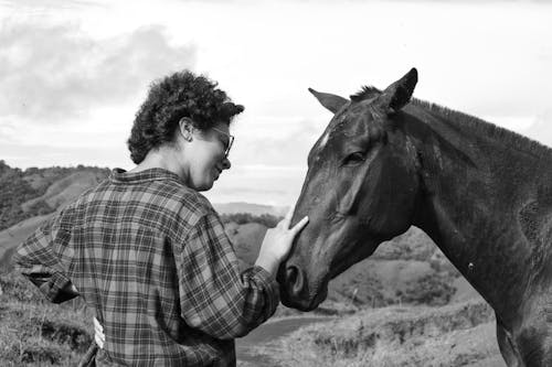 Black and White Photo of a Young Woman with a Horse in a Hilly Landscape