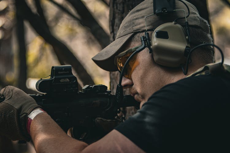 Man In Tactical Protective Headset And Eyeglasses Aiming His Rifle For A Target