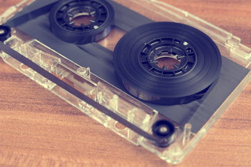 Clear and Black Cassette Tape on Brown Wooden Surface