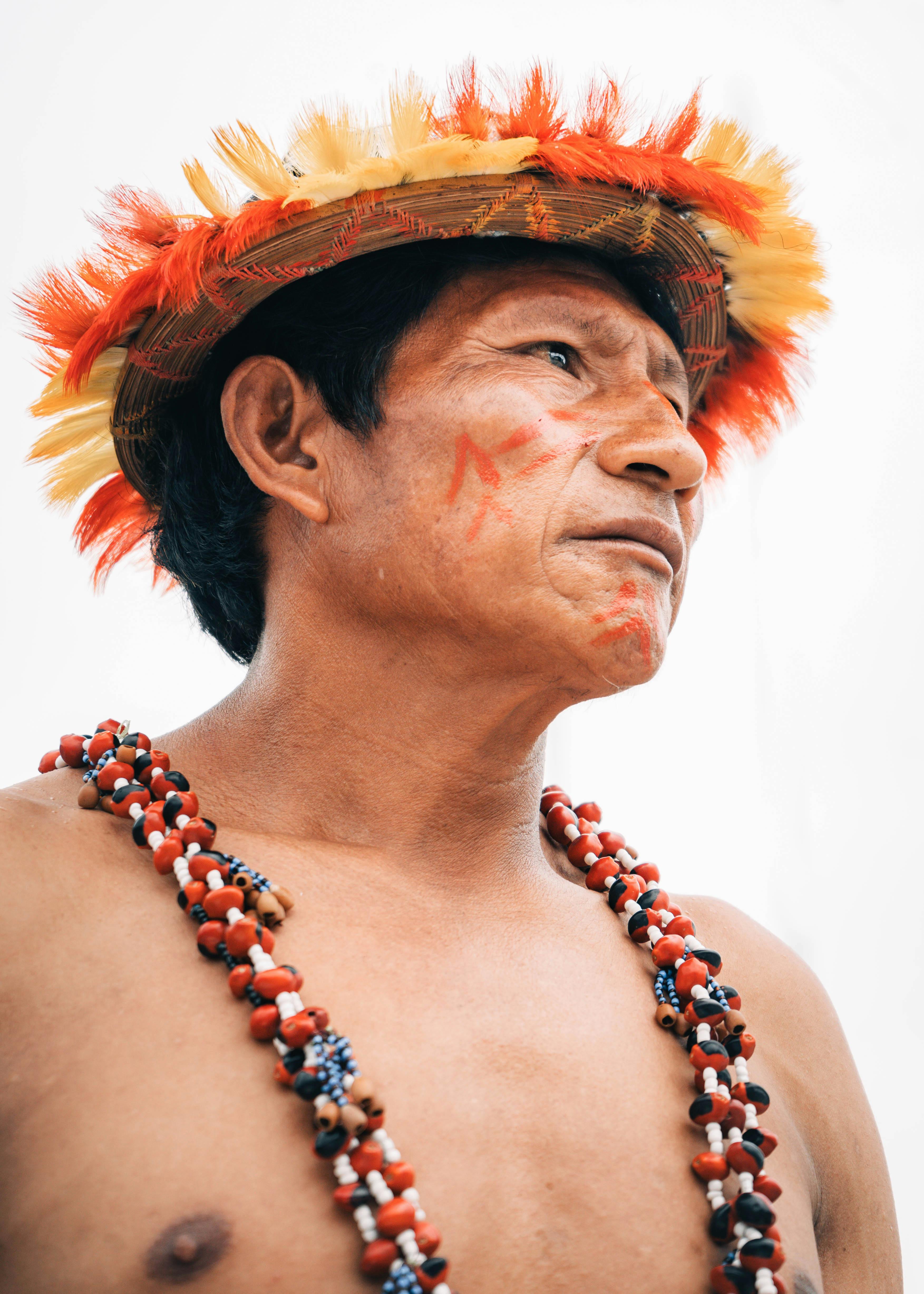 Portrait of an indigenous man in traditional attire with a vibrant feathered hat in San Martín, Peru.