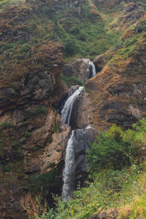 Free Beautiful cascading waterfall in Huarochirí, Peru surrounded by lush greenery and rocky cliffs. Stock Photo