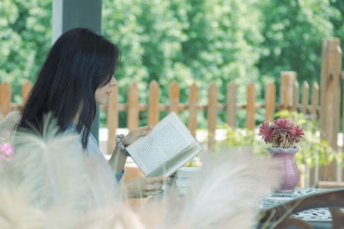 Young Woman sitting on a Terrace and Reading a Book 