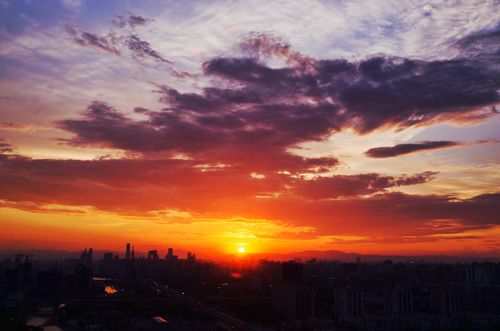 Free Majestic sunset casting vibrant hues over the city skyline and clouds. Stock Photo