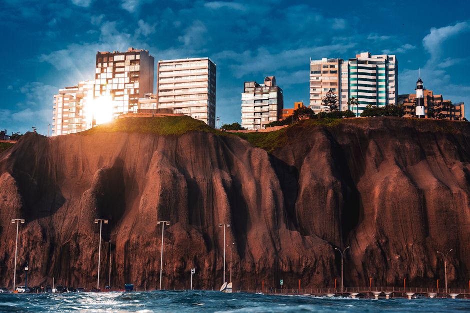 Scenic view of Miraflores cliffs with modern buildings illuminated by sunset light, Lima, Peru.