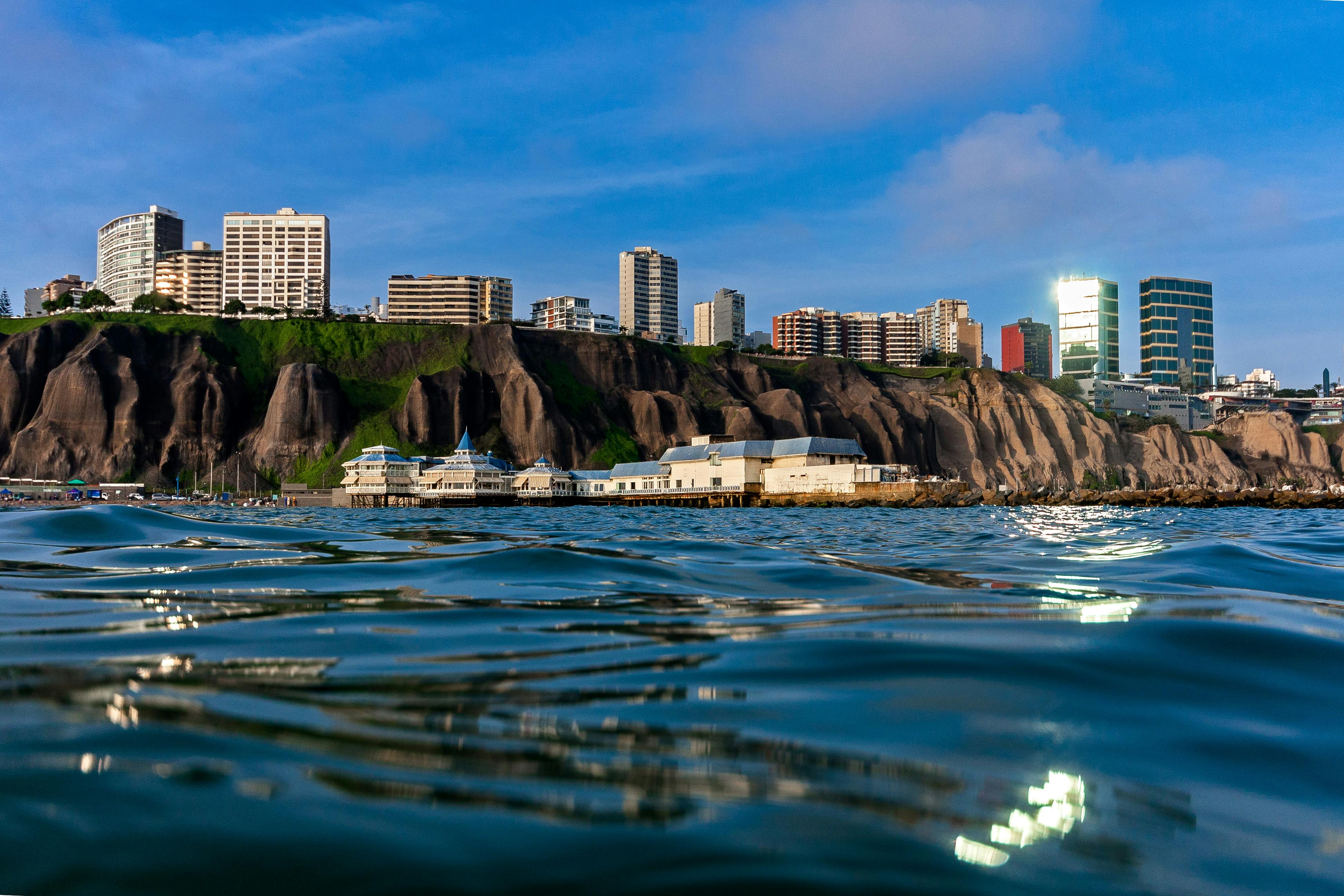 Skyline of Lima's coast featuring residential buildings on cliffs with ocean reflection