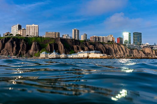 Skyline of Lima's coast featuring residential buildings on cliffs with ocean reflection